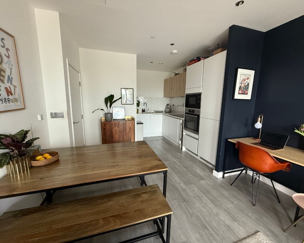 Photo of the open-plan living space showing the dining table, a home office space and the kitchen