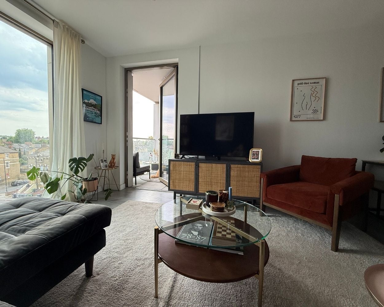 Photo of the open-plan living space showing the full height windows and a door leading to the balcony