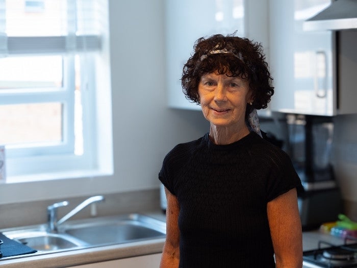Belinda smiling as she stands for a photo in her kitchen