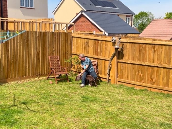 Paul sits on a chair in the sunshine in his garden.