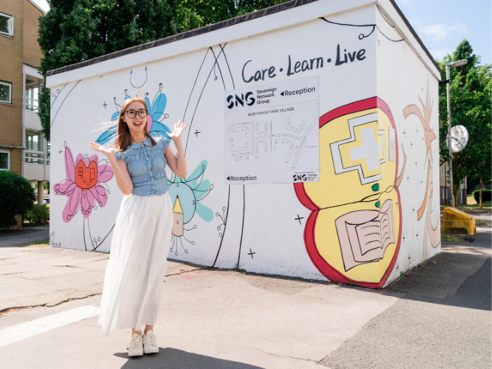 Danling Su poses for a picture in front of her finished mural at Northwick Parkside
