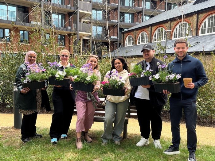 The residents proudly hold up their planters whilst stood in the communal garden area at The Restorey.
