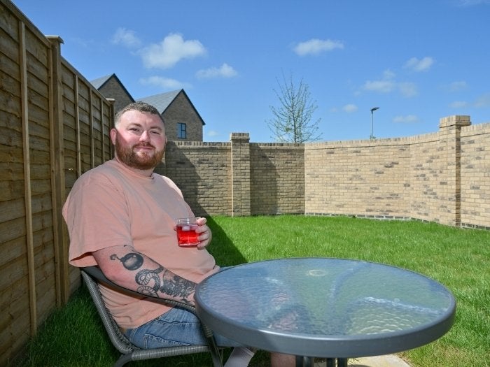 Ethan enjoys a cold drink at his garden table on a sunny day.