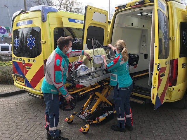 Ambulanceverpleegkundigen plaatsen brancard met couveuse in de ambulance