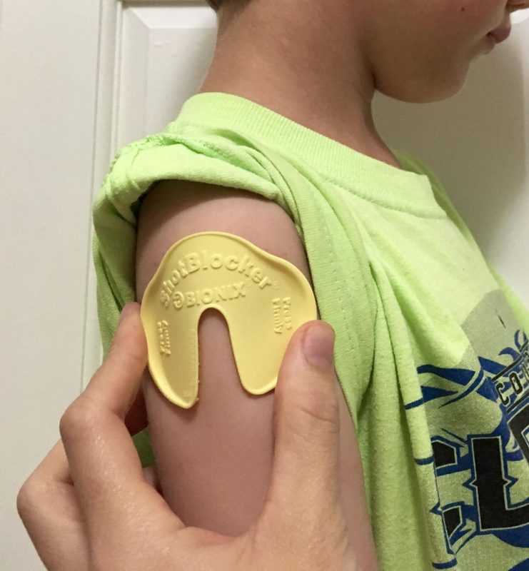 shotblocker geel U-vormig object op de arm van een kind, vermindert de pijnbeleving