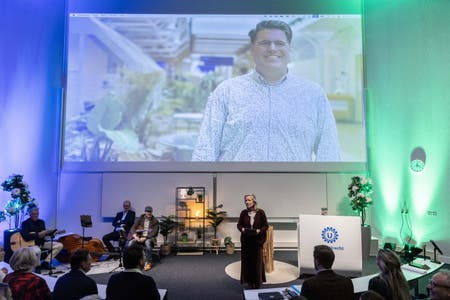 Carina Hilders spreekt tijdens de uitreiking van de Boerhaaveprijs 2025 in de collegezaal. Op het grote scherm staat een foto van winnaar Ralph Wijnhoven. 