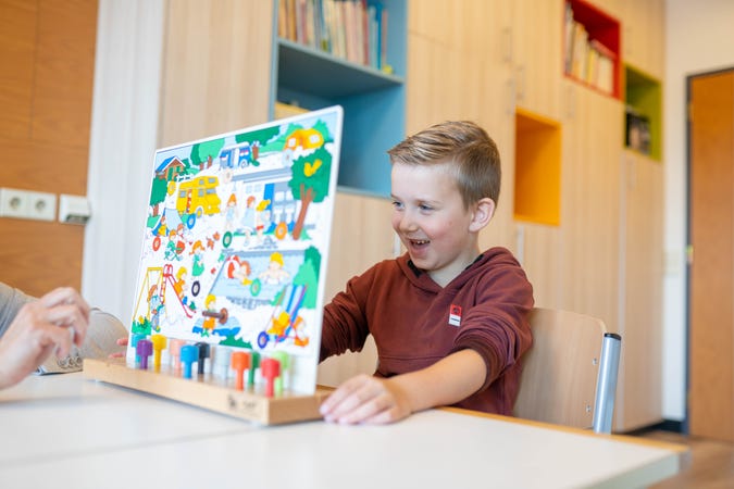 Een kind doet een spelletje aan tafel.