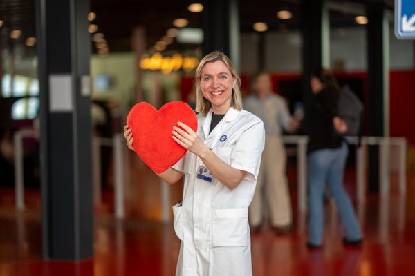 Een vrouw (Linda van Laake) in een witte jas met een rood hart.