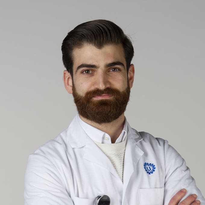 Een man met baard en snor in een witte labjas