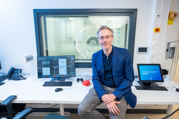 Alessandro Sbrizzi die op een bureau zit, voor een computerscherm met de MRI op de achtergrond