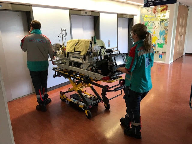 Ambulanceverpleegkundigen bij brancard met couveuse wachten op de lift
