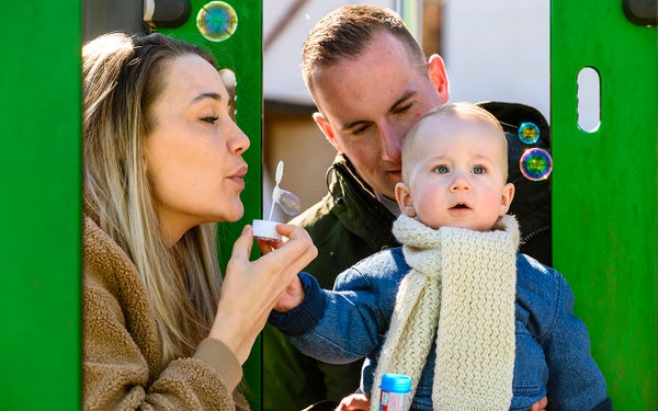 Ouders van baby Maxim blazen zeepbellen en Maxim volgt de bellen aandachtig