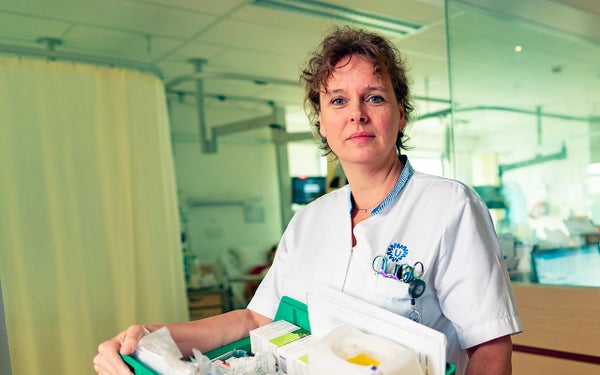 Een verpleegkundige die staat op de gang met een doos spullen in haar hand