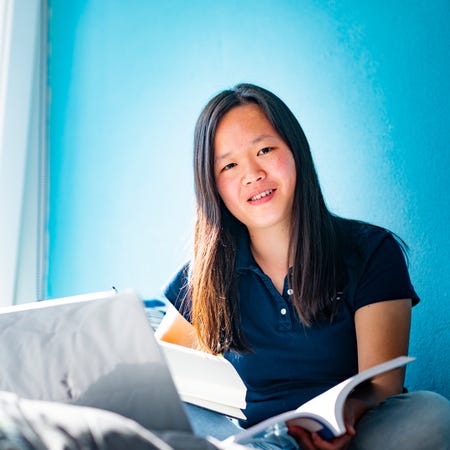 Een vrouw op een bank met een boek en een laptop