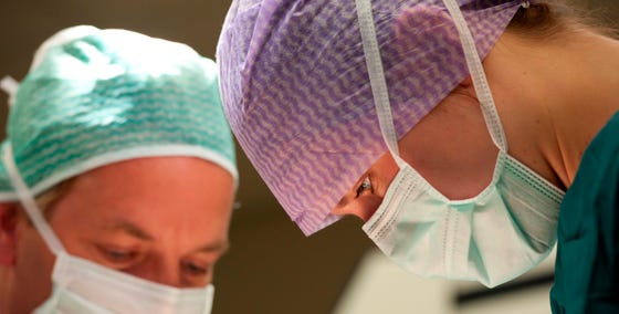 Een close-up van een paar artsen met chirurgische hoofddeksels en neusmondmaskers op.