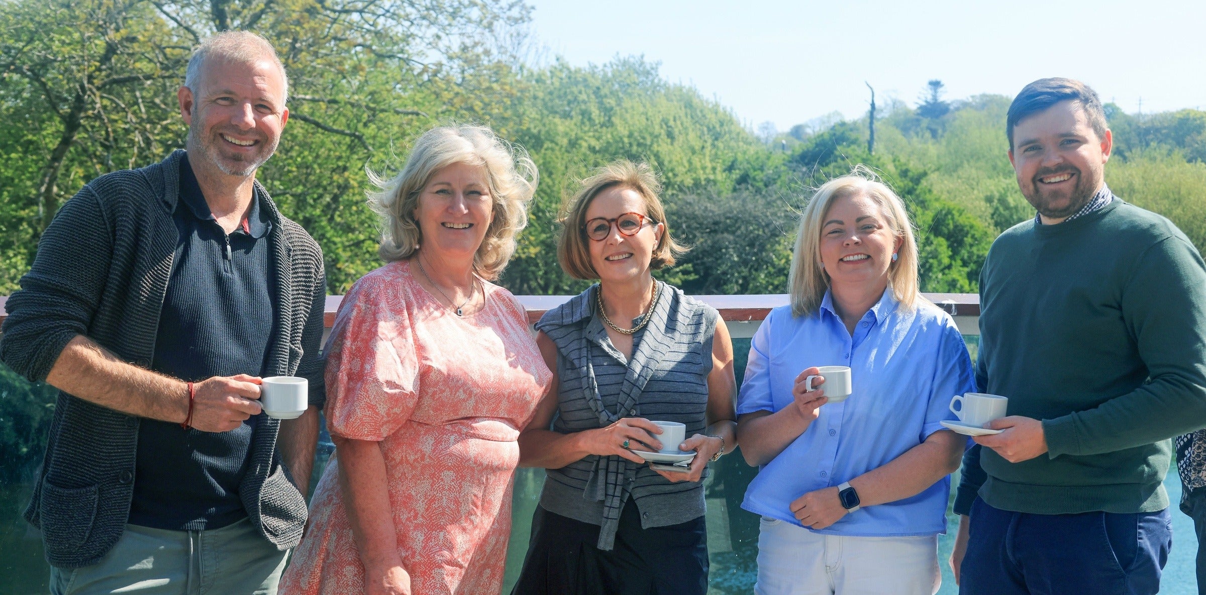 Networking group attendees pose outside with tea cups.