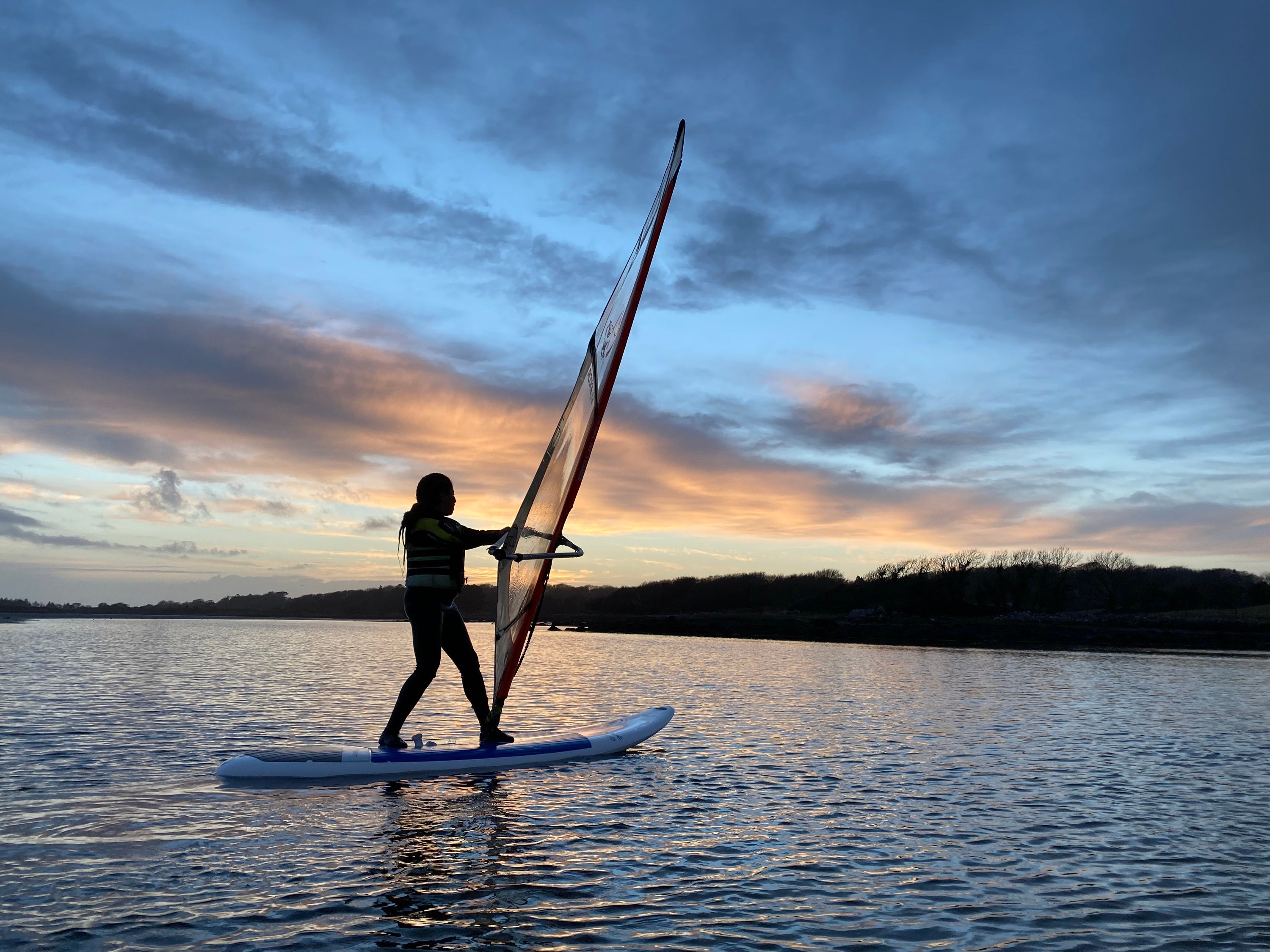 A person on a surfboard with a sail