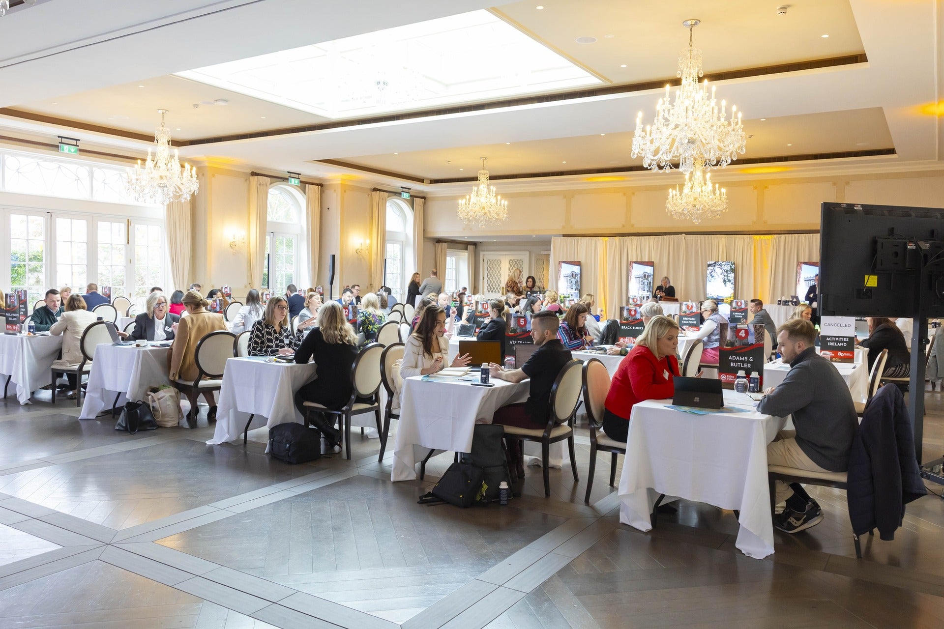 Tourism trade buyers and sellers at round tables in an elegant chandelier-lit ballroom during a workshop event