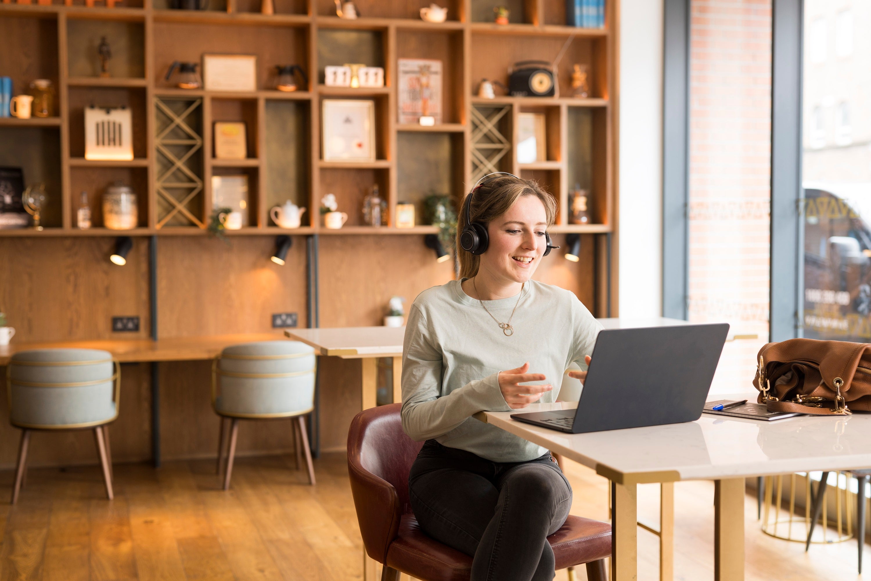 A woman wearing headphones and sitting at a table with a laptop.