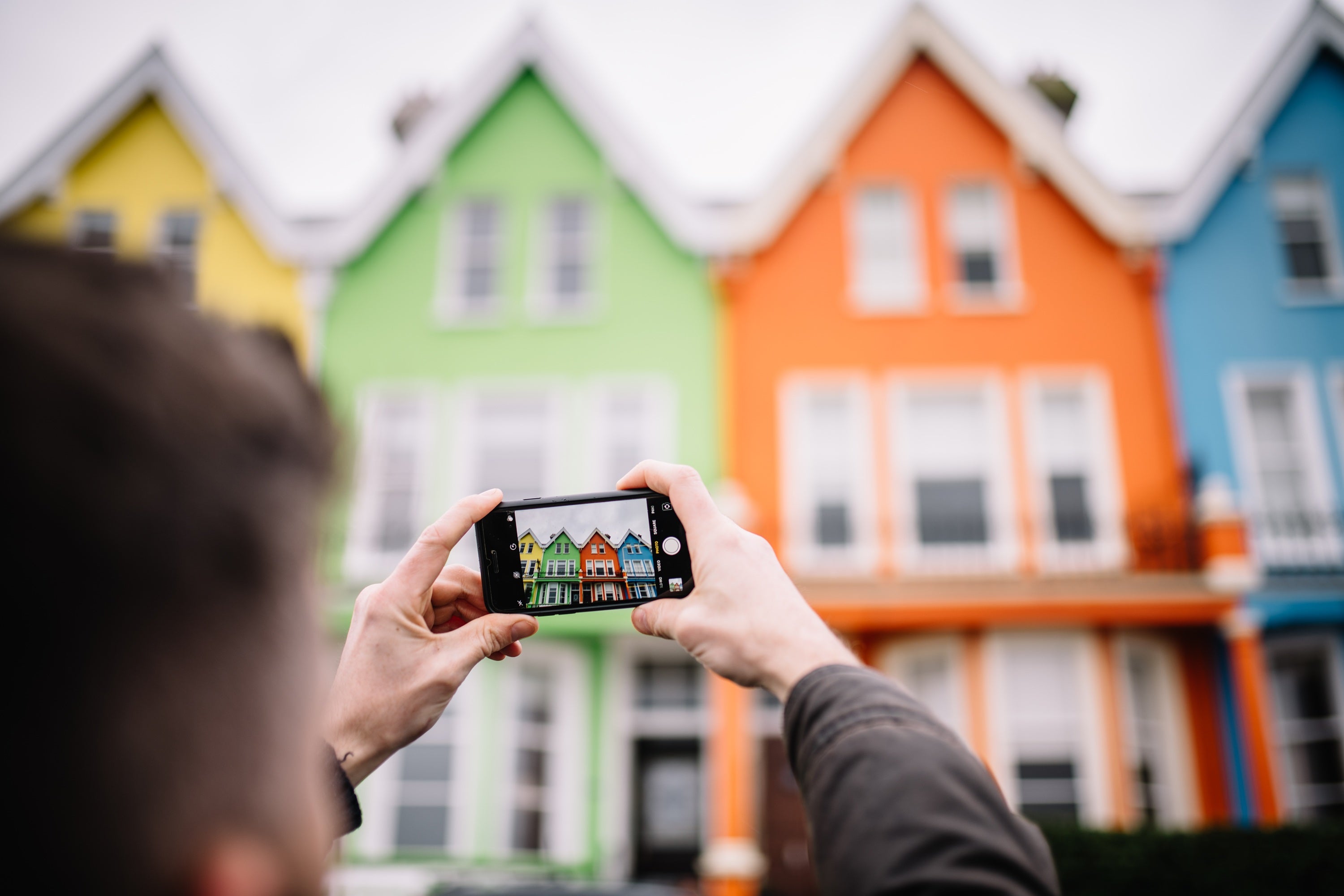A person holding a phone with a picture of houses in the background