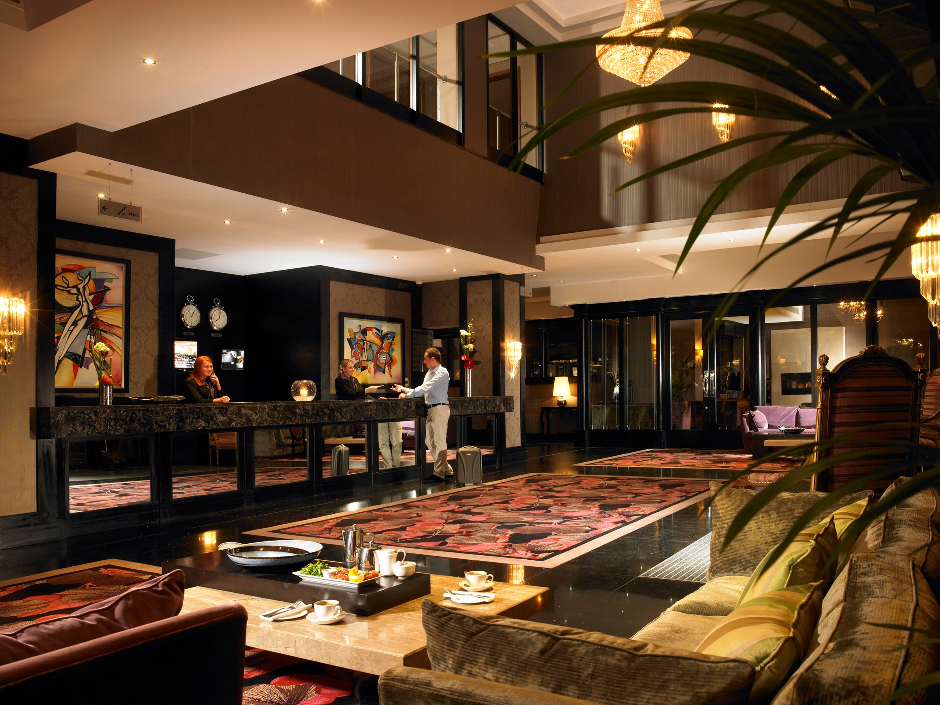 A hotel lobby with a couple of people standing behind the counter