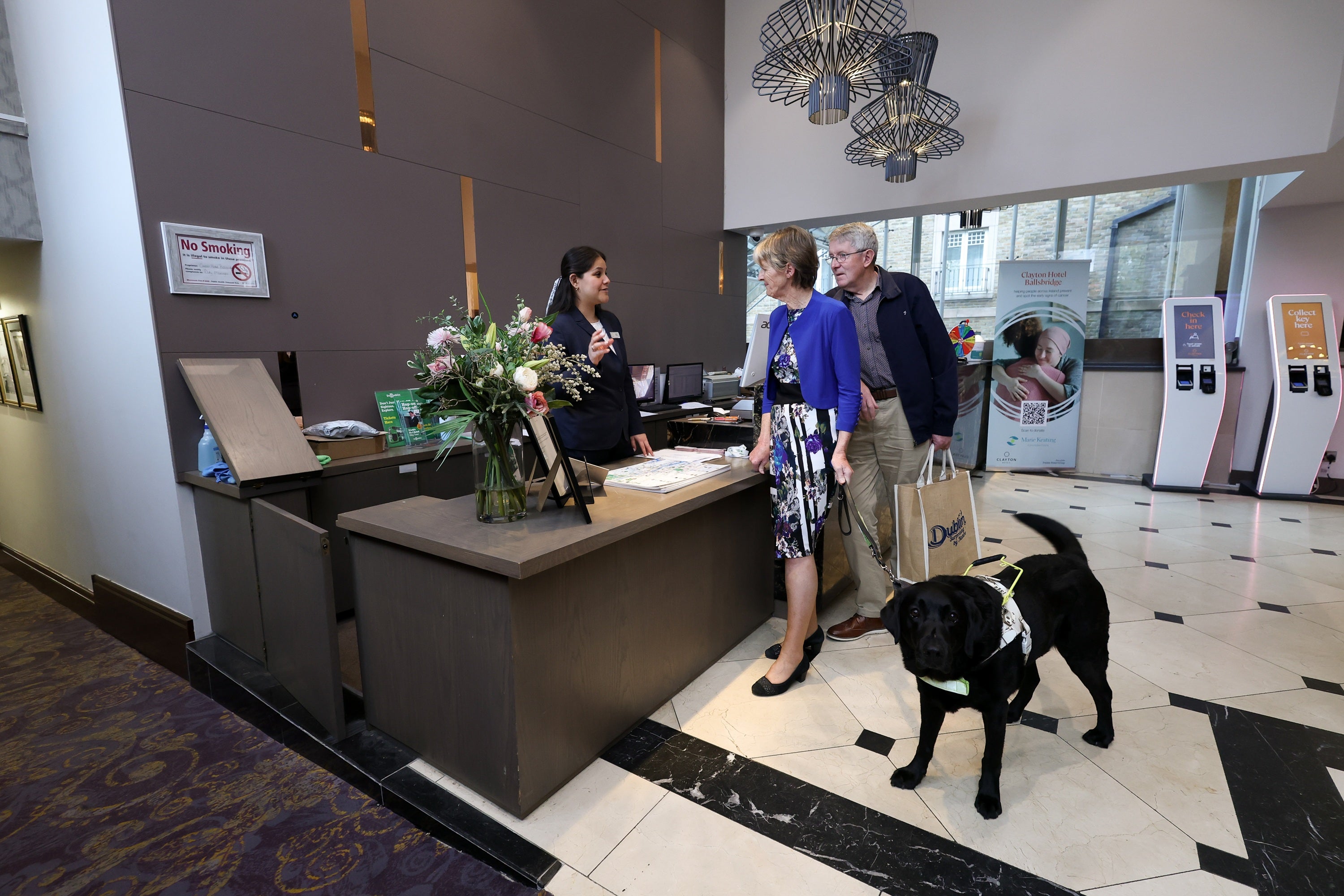 A group of people standing at a reception desk with a dog