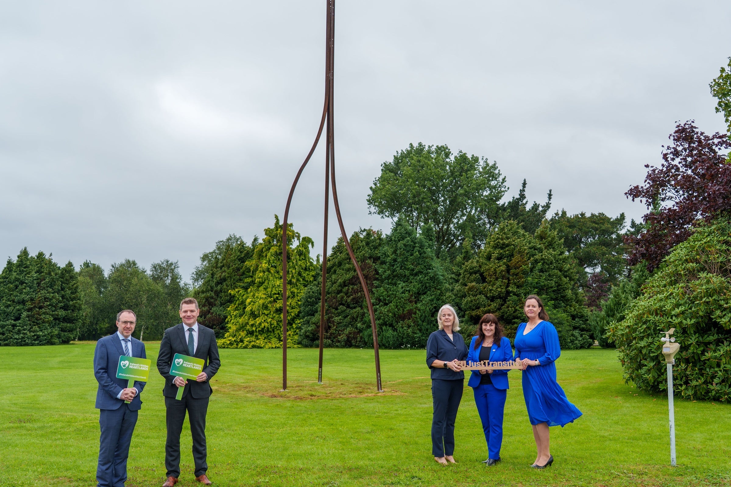 Minister O'Brien and stakeholders pose for photo in front of sculpture.