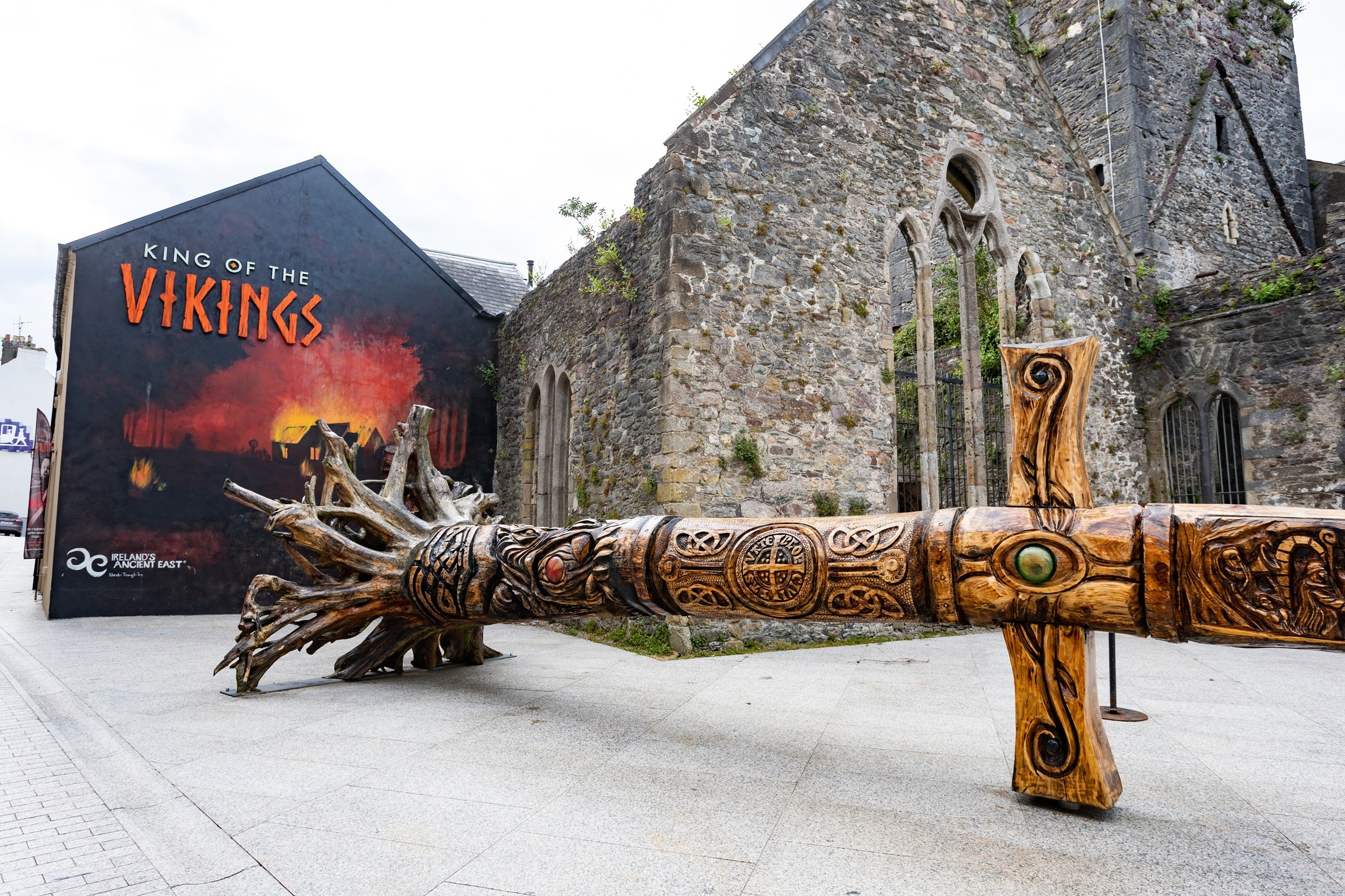 A large wooden sword in front of a stone building