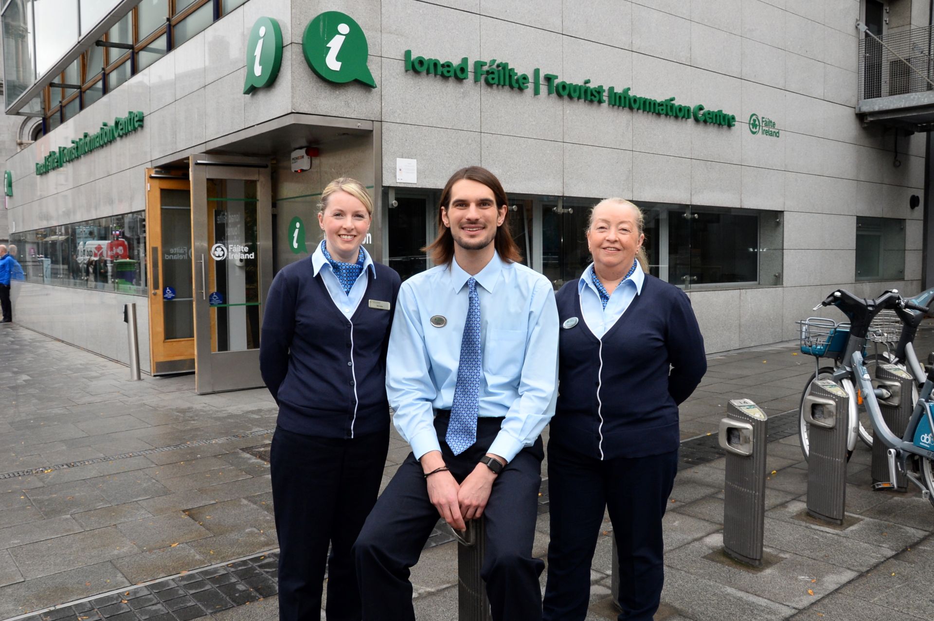 Three staff members standing outside a Fáilte Ireland tourist information centre