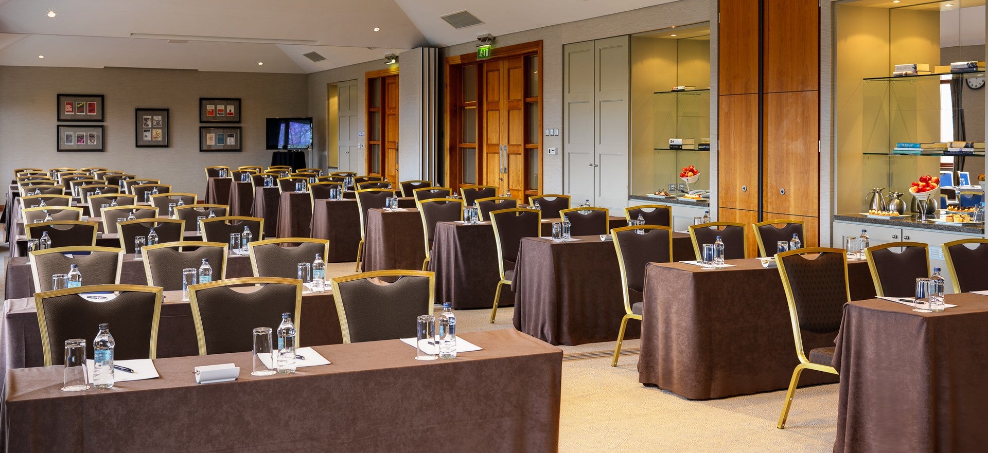 Conference room set up in classroom style with rows of tables, water bottles, and notepads