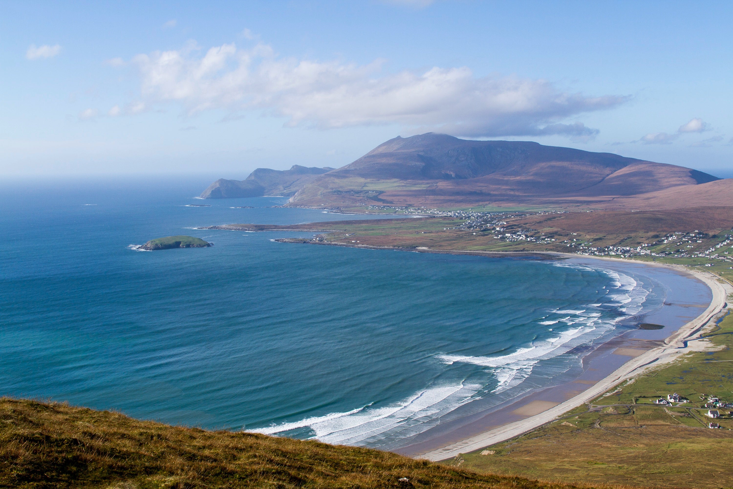 A beach with a road and mountains in the background