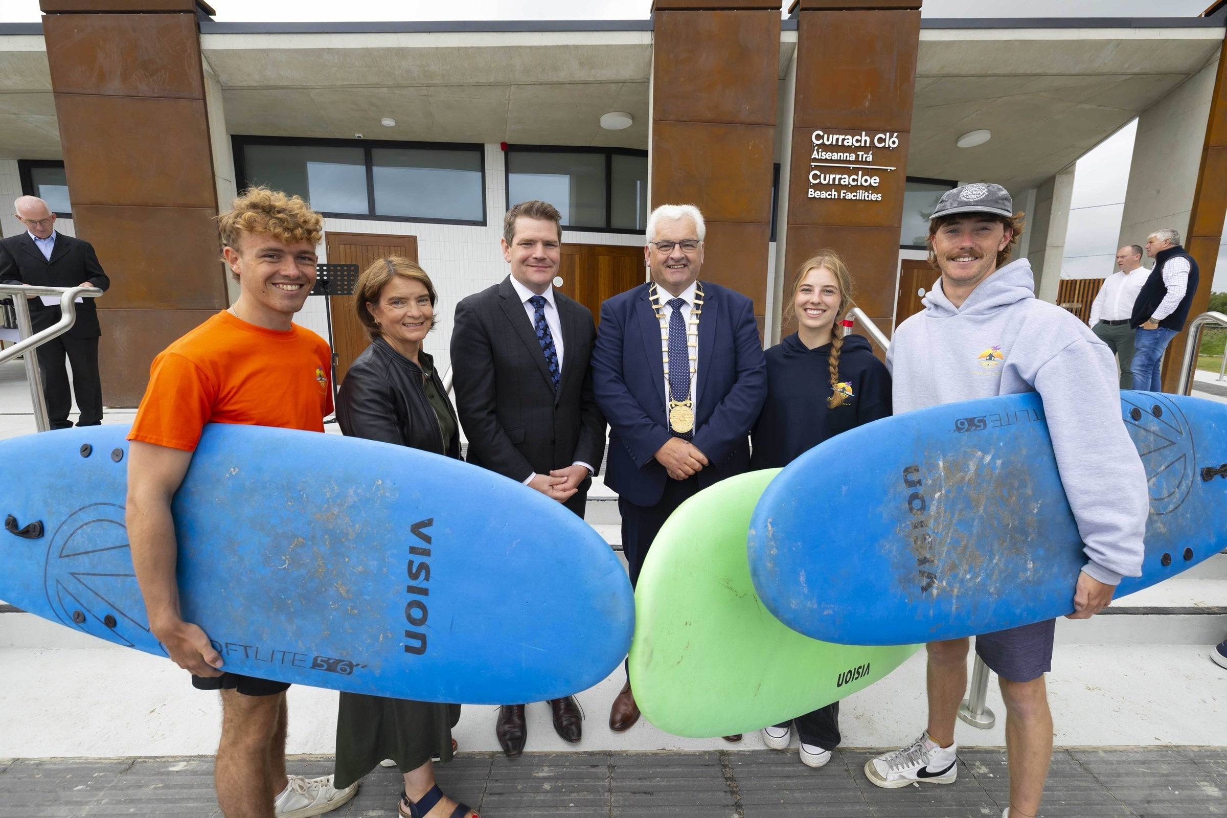 Stakeholders and people with surfboards pose for a photo in front of the new water sports centre.