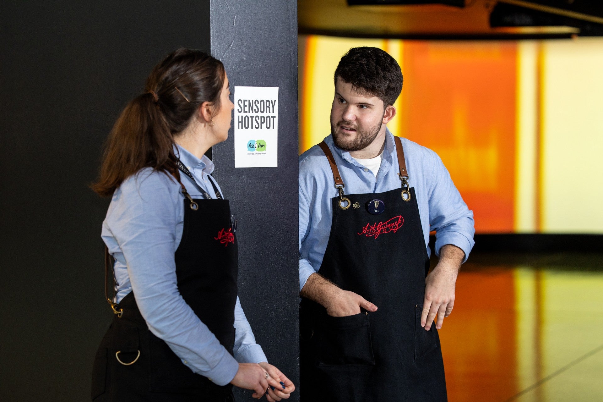 Two staff members in Guinness Storehouse aprons in conversation beside a sensory hotspot display