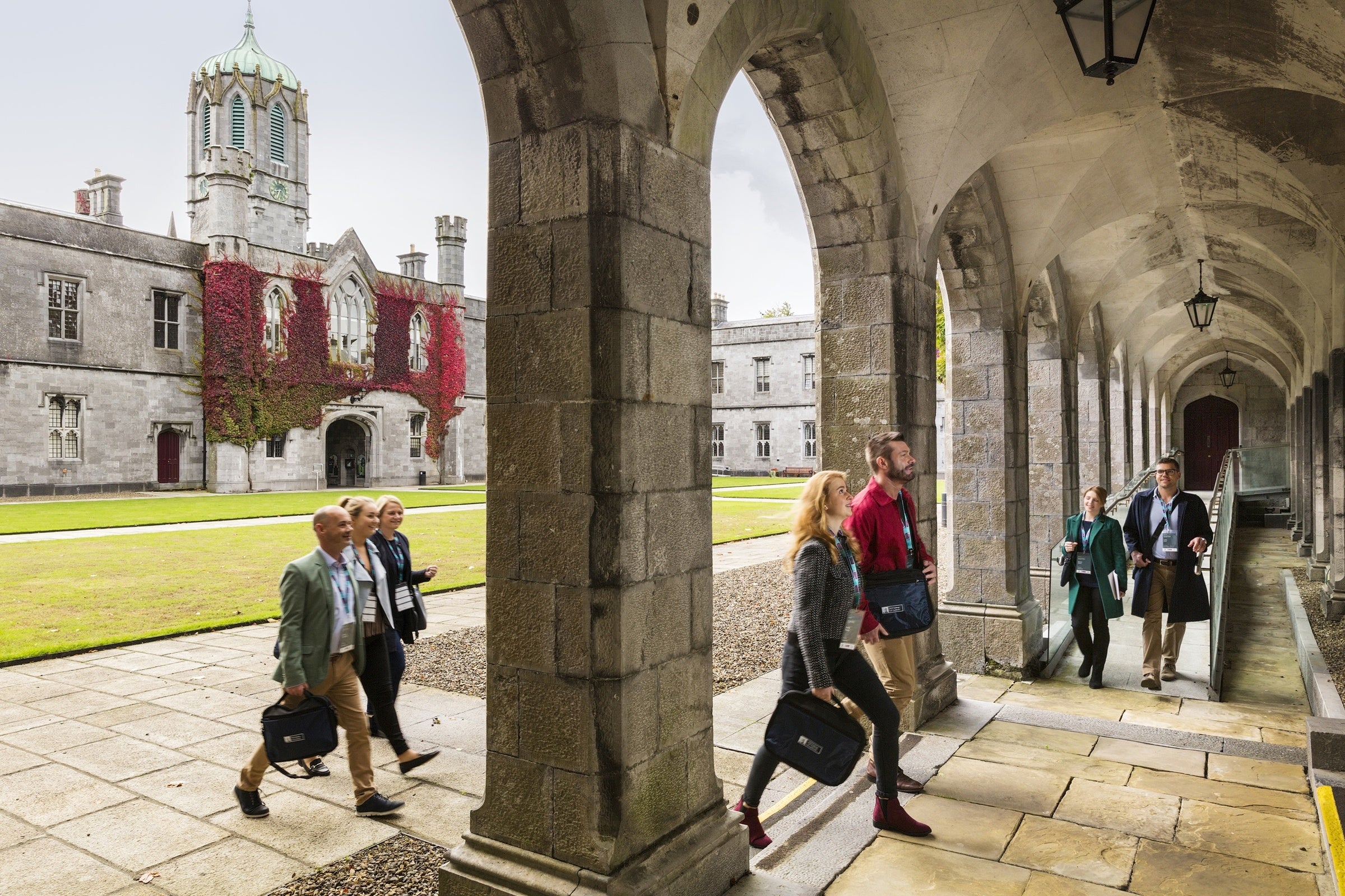 People walk through stone arches from an internal court yard.