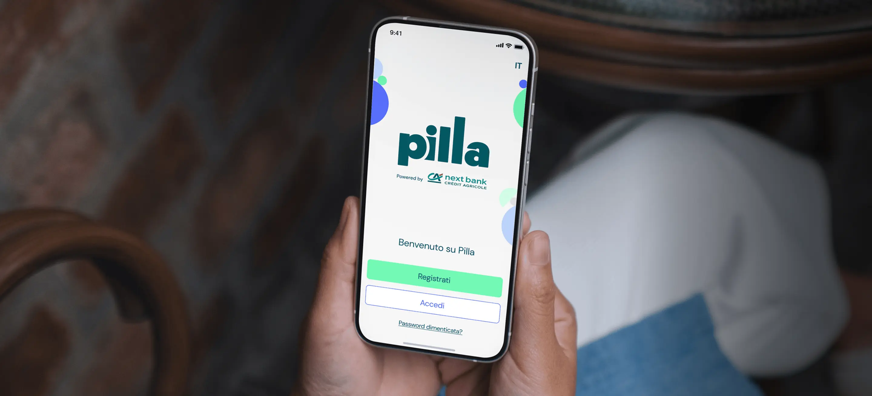 Le mani di una persona tengono uno smartphone che mostra la schermata di benvenuto dell'app Pilla.