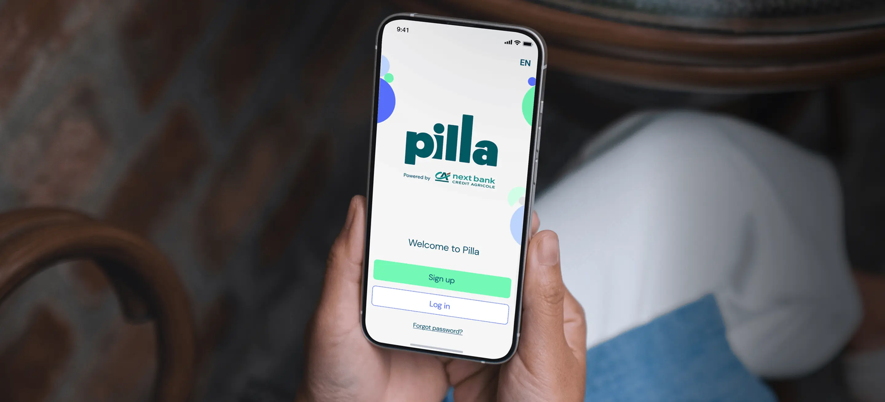 A person's hands hold a smartphone displaying the Pilla app's welcome screen.