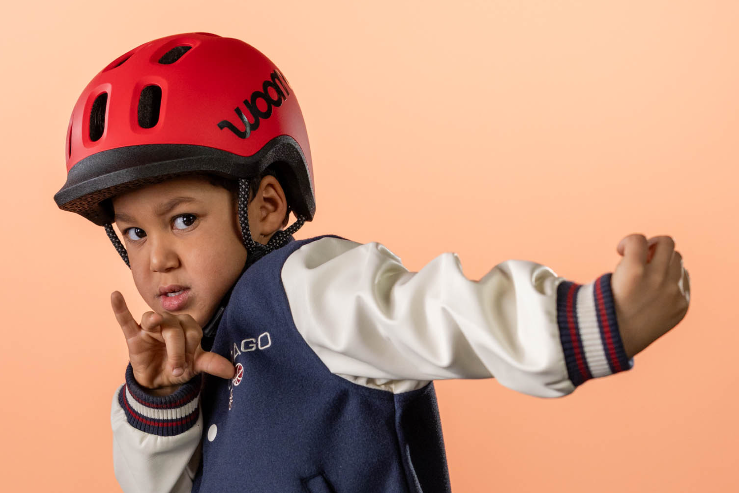 A young boy is wearing a new red woom helmet on his head and looking cool as he poses for the camera.