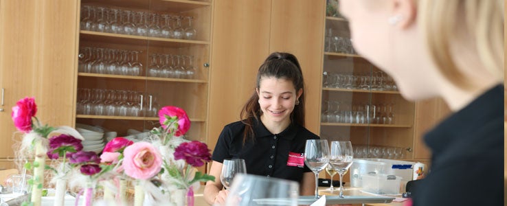 Schülerin beim Eindecken eines Tisches