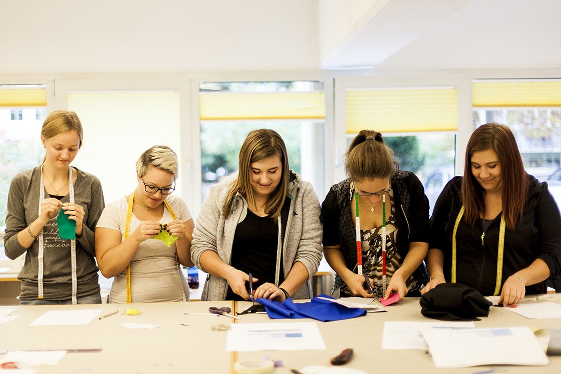 Schülerinnen  beim Stoffzuschnitt und nähen von Hand 