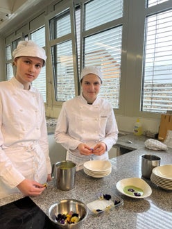 Zwei Schülerinnen beim Garnieren der Suppe mit frischen Blüten