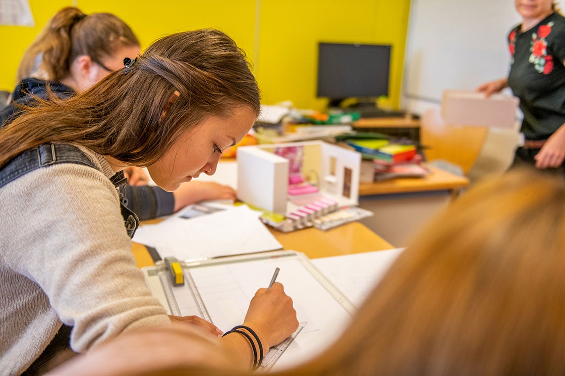 Schülerinnen beim Modellbau. Schülerin zeichnet eine Raumskizze.