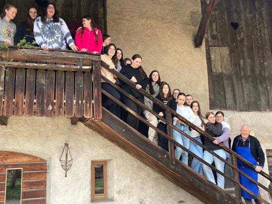 Gruppenfoto der 3. Klasse. Die Schülerinnen und der Hofbesitzer stehen auf einer hölzernen Außentreppe.