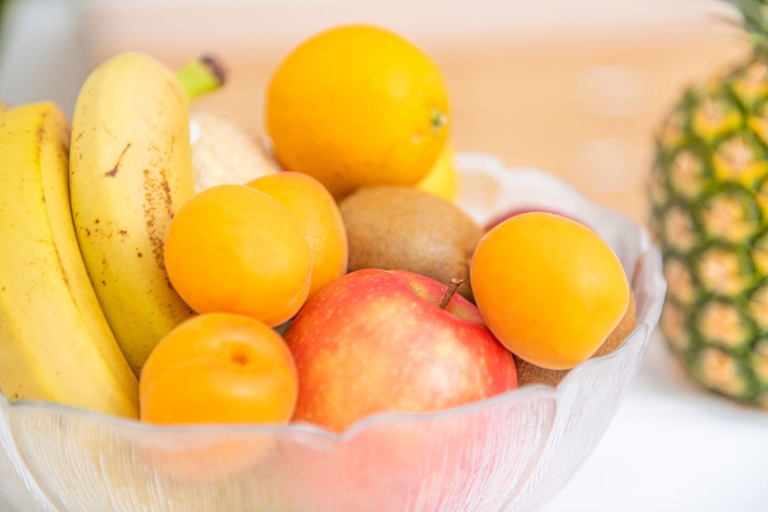 Obstschüssel mit Marillen, Apfel, Kiwi, Bananen und einer Ananas