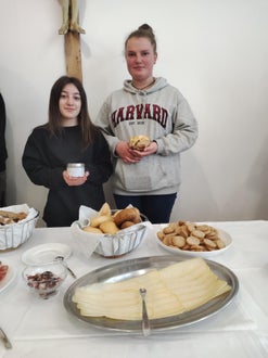 Zwei Schülerinnen halten bäuerlichen Produkten in ihren Händen und im Vordergrund steht eine Käseplatte und Brot.