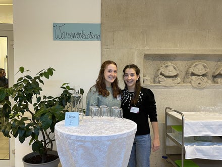 Zwei Schülerinnen im Eingangsbereich der Schule bei der Wasserverkostung