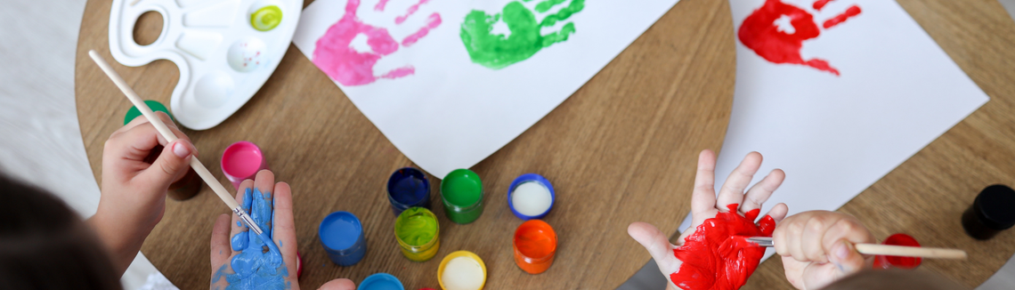 Gyermek kézlenyomatok és festékek egy asztalon