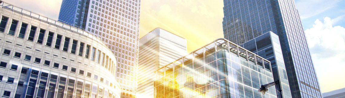 Високи бизнес сгради с размазани нощни светлини на преден план.