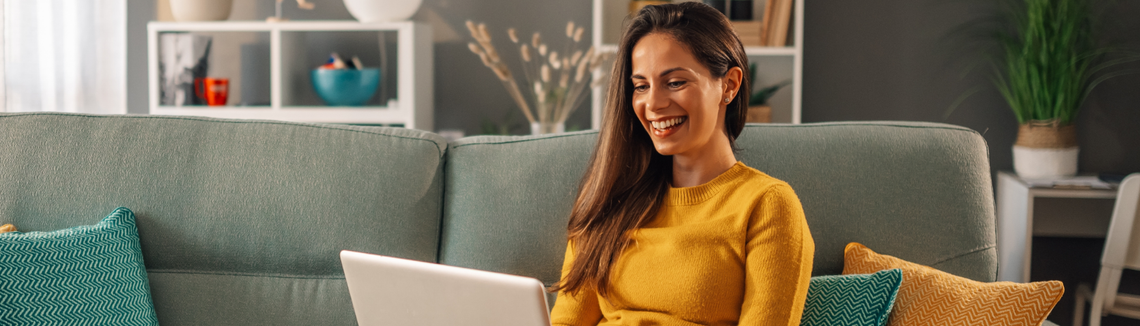 Egy nő mosolyog, miközben laptopot használ