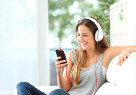 Žena so slúchadlami na ušiach a pozerajúca sa na telefón