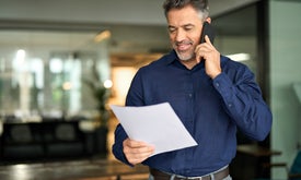 Muž, ktorý drží papier a telefonuje z mobilu